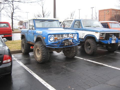 1994 Ford Bronco - A lifted blue 1978 Ford Bronco is parked next to another truck, both modified for off-road use.