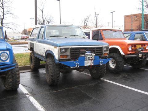 1994 Ford Bronco - Modified Ford Bronco from the 1980s, parked alongside other off-road vehicles.