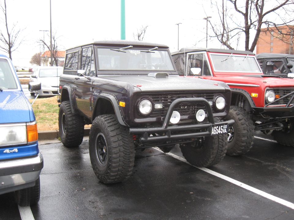 Dark purple Ford Bronco with a hood scoop, bull bar, and large off-road tires