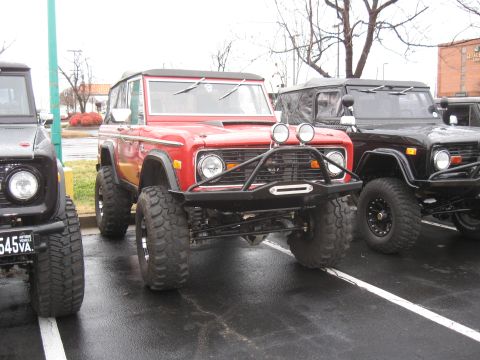 1994 Ford Bronco - A red 1978 Ford Bronco is parked in a lot with other Broncos, a custom bumper and off-road tires.