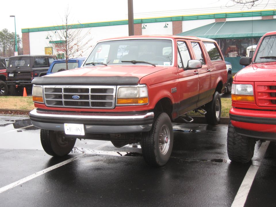 Red 1994 Ford Bronco parked next to another red truck