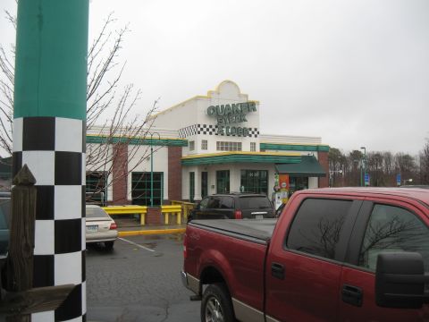 1994 Ford Bronco - A red pickup truck and a black SUV are parked in front of a Quaker Steak & Lube restaurant.