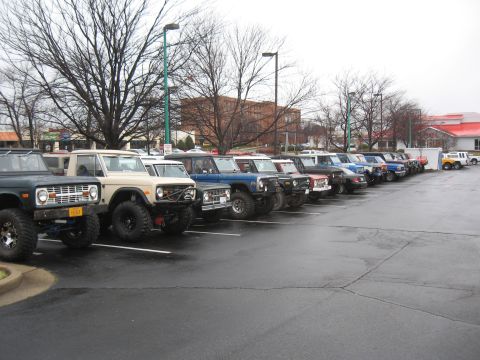 1994 Ford Bronco - A line of Ford Broncos, including a tan 1978 model, are parked in a lot on an overcast day.