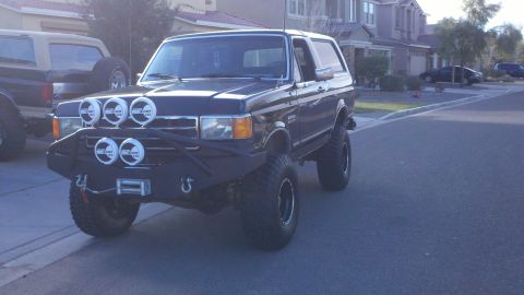 1991 Ford Bronco - Modified 1991 Ford Bronco with off-road lights and bumper, parked next to another Bronco.