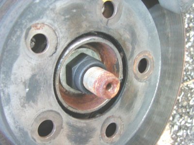 1997 Ford Taurus - Close-up view of a corroded wheel hub assembly, showing a large hex nut and threaded bolt.