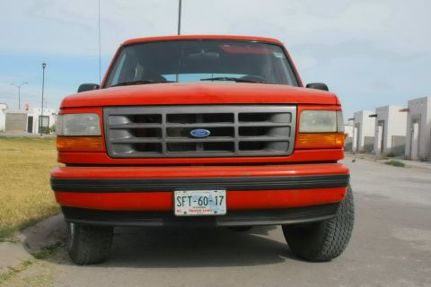 1995 Ford Bronco - Front view of a red Ford Bronco, likely a 1992 model, parked outdoors.
