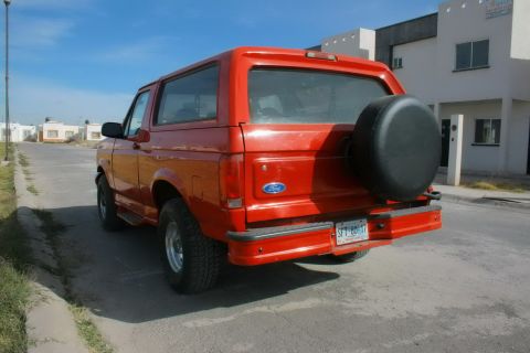 1995 Ford Bronco - Rear view of a red 1995 Ford Bronco parked on a residential street.