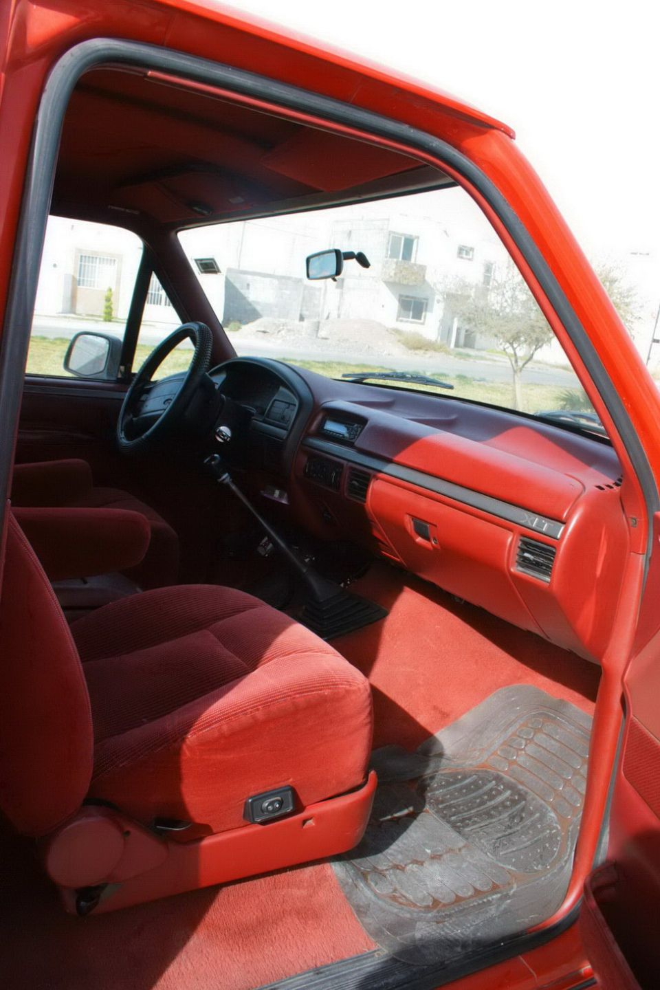 Red interior of a 1995 Ford Bronco, showing the dashboard, seats, and door panel