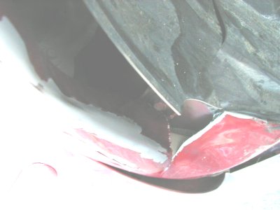 1997 Ford Taurus - The fender liner appears to be damaged, with exposed white primer beneath the red paint.
