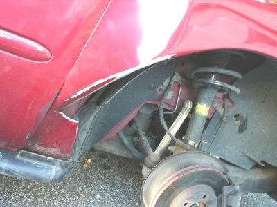 1997 Ford Taurus - Damage to the fender and wheel well of a red car is visible, showing suspension parts.