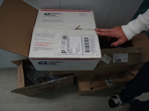 1993 Ford Taurus - Several USPS Priority Mail boxes are stacked, with one open and a hand reaching in.