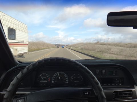 1993 Ford Taurus - Driving on the highway with a trailer in tow and other vehicles on the road under a cloudy sky.