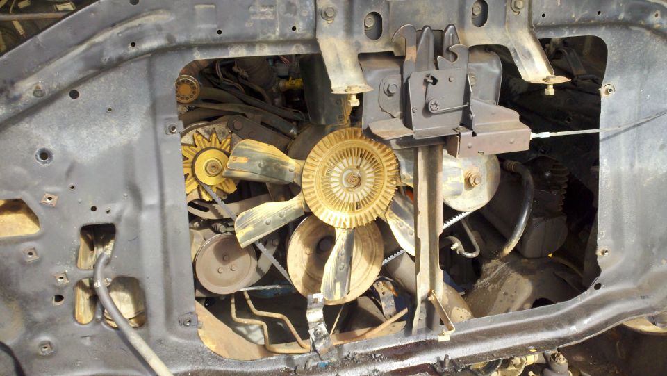 Engine bay with yellow fan, belts, and pulleys. The hood is open
