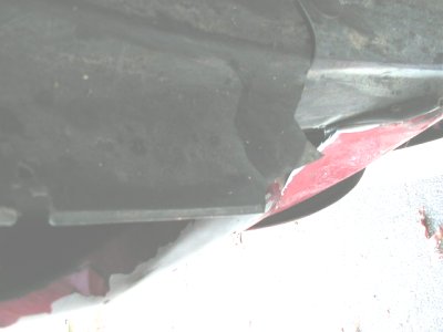 1997 Ford Taurus - Underbody view shows a damaged panel with red paint peeking through.