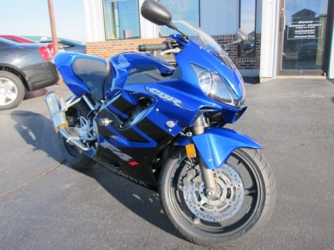 1999 Mercury Grand Marquis - A blue Honda CBR motorcycle is parked in front of a building, with a black car visible to its left.
