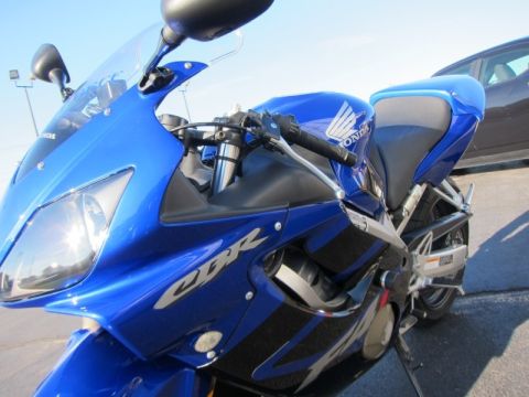 1999 Mercury Grand Marquis - A blue Honda CBR motorcycle is shown from the front quarter angle, with a car visible in the background.