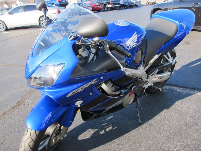 Blue Honda CBR sportbike parked outside, with other cars in background