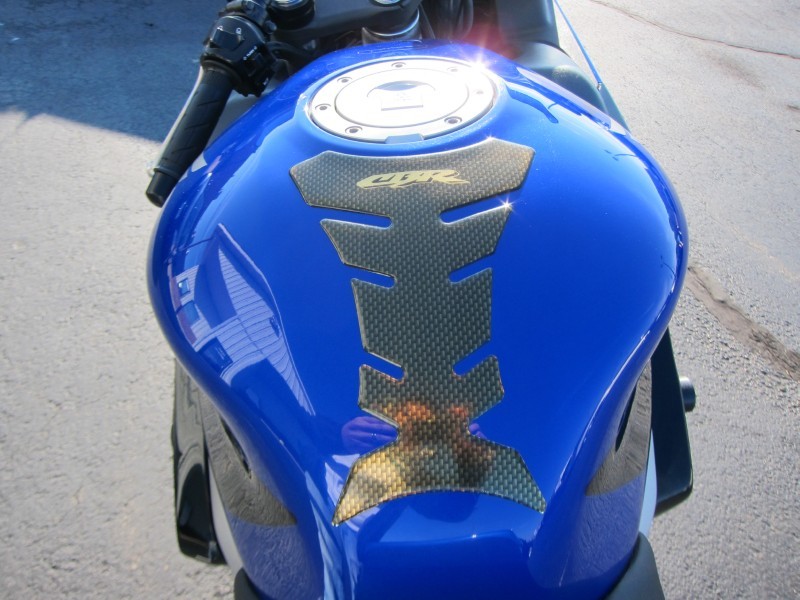 Blue motorcycle fuel tank with gold CBR emblem and carbon fiber grip pad