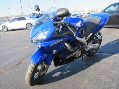 1999 Mercury Grand Marquis - A blue Honda CBR motorcycle is parked outdoors on a paved surface with other vehicles in the background.