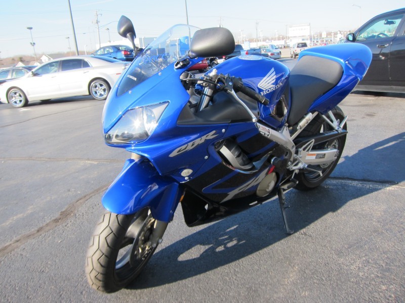 blue Honda CBR motorcycle parked on pavement, with cars in background