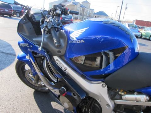 1999 Mercury Grand Marquis - A blue Honda CBR motorcycle is parked outdoors, with a reflection of a person in the fuel tank.