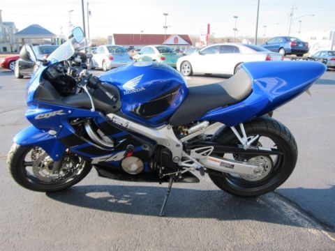 1999 Mercury Grand Marquis - A blue Honda CBR motorcycle is parked outside with other vehicles in the background.