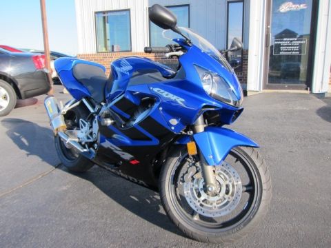 1999 Mercury Grand Marquis - A blue Honda CBR motorcycle is parked in front of a building with glass doors.