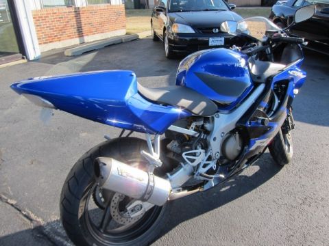 1999 Mercury Grand Marquis - A blue sport motorcycle is parked on asphalt, with a black car visible in the background.