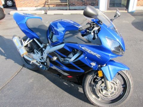1999 Mercury Grand Marquis - A bright blue Honda CBR sportbike is parked on an asphalt surface. The motorcycle features a silver exhaust pipe and black accents on its f…