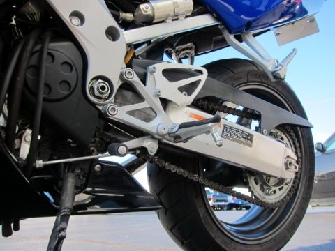 1999 Mercury Grand Marquis - Close-up view of a motorcycle's rear wheel and drivetrain components, with another vehicle in the background.