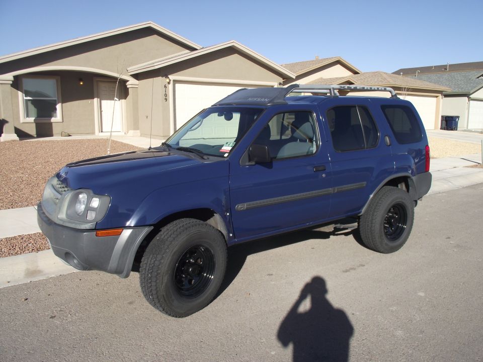Dark blue Nissan Xterra SUV with black steel wheels parked on a residential street, front three-quarter view