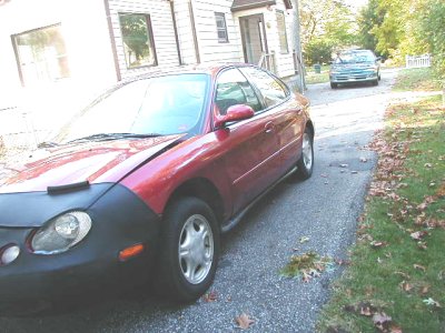 1997 Ford Taurus - A red sedan with a black car bra is parked on a driveway, with another vehicle in the distance.