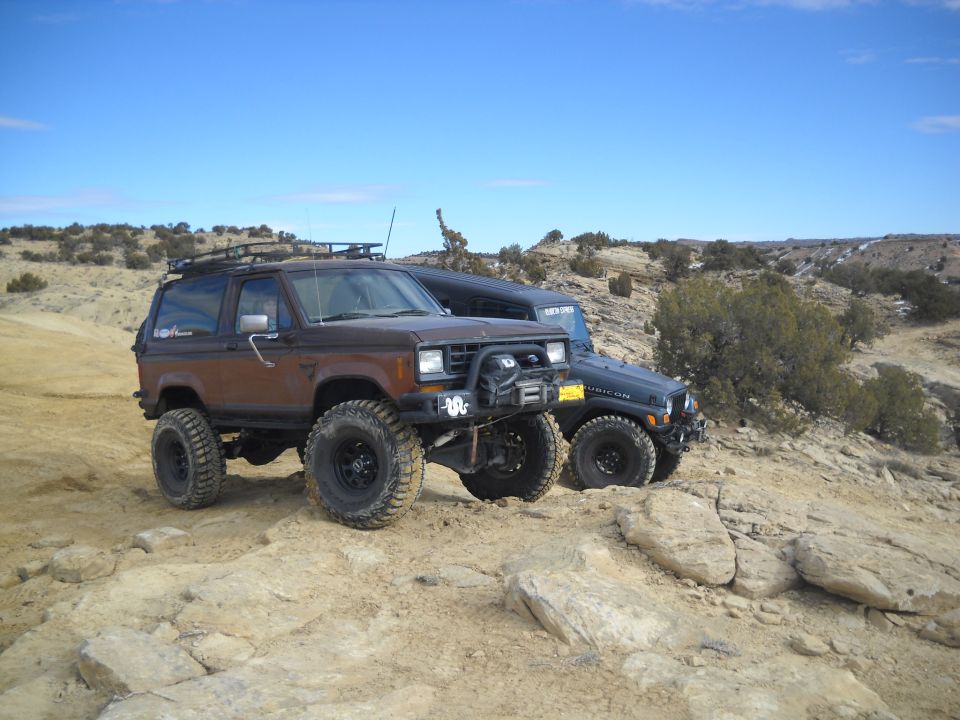 Brown Ford Bronco II with roof rack and off-road tires parked on rocky terrain