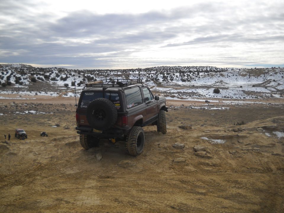 Brown SUV with spare tire on rear, off-road tires, and roof rack