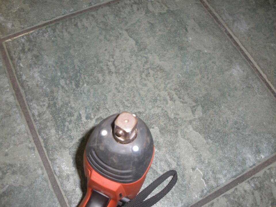 Socket wrench attachment on a power tool on a tiled floor.
