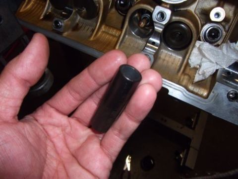 1991 Ford Taurus - A hand holds a valve tappet, with the engine block and its internal components visible in the background.