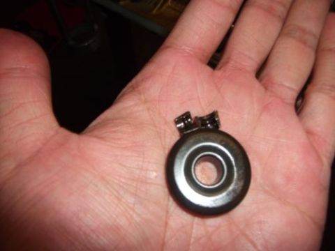1991 Ford Taurus - A small metal part is held in a person's hand, with a website logo visible at the bottom right.