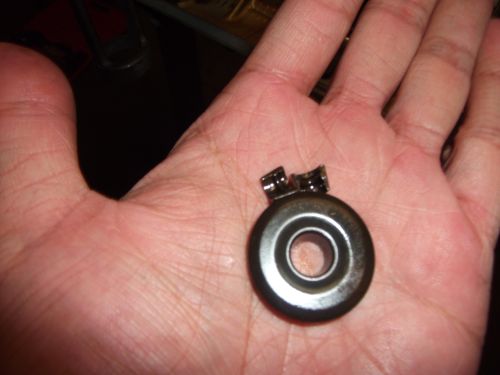 Part held in a palm, showing a circular metal component with two small clips