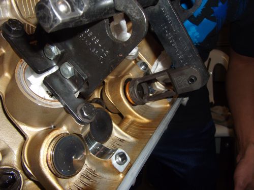Engine valve spring compressor tool on engine block with visible parts