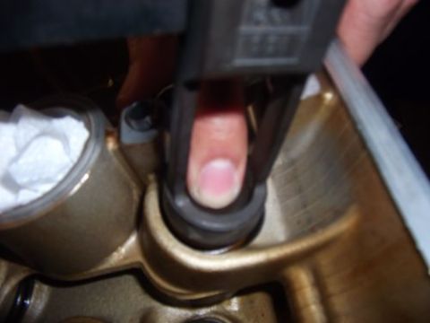 1991 Ford Taurus - A finger operates a tool on an engine component, with a white material visible in a nearby container.