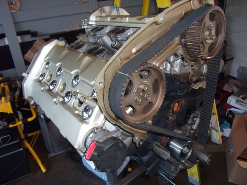 Engine with timing belt and pulleys, mounted on a stand. Supermotors.net logo visible