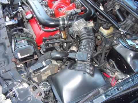 1991 Ford Taurus - Close-up view of an engine bay, a red intake manifold and visible V6 DOHC text on a black pipe.
