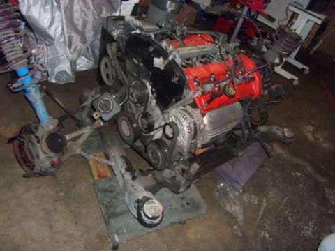 1991 Ford Taurus - Engine and front suspension components are laid out on the floor, possibly for repair or replacement.