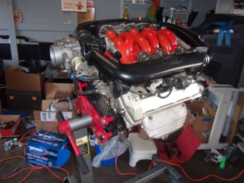 1991 Ford Taurus - Engine assembly on a stand in a workshop setting with various parts and boxes visible.