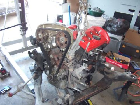 1991 Ford Taurus - An engine is being worked on, suspended by a hoist in a garage setting.