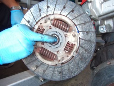 1991 Ford Taurus - A gloved hand holds a clutch disc, part of an engine swap.