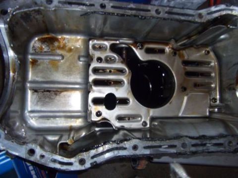 1991 Ford Taurus - This is a close-up view of an engine oil pan, showing signs of wear and oil accumulation.