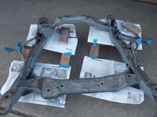 Gray metal subframe on newspapers, blue tape, wooden blocks