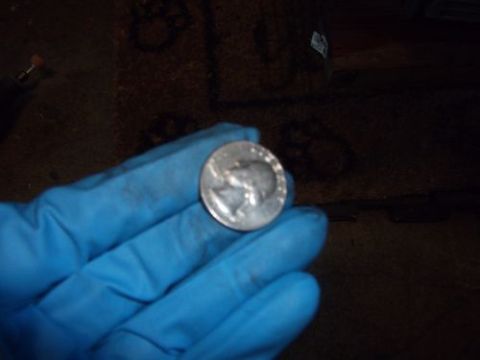 1991 Ford Taurus - A quarter is held in a blue gloved hand against a dark, out-of-focus background.