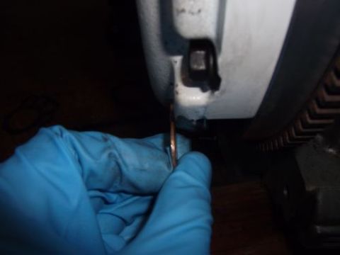 1991 Ford Taurus - A gloved hand holds a copper washer near an engine component, possibly during a repair or modification.